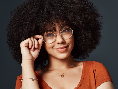 woman with curly hear wearing circular glasses