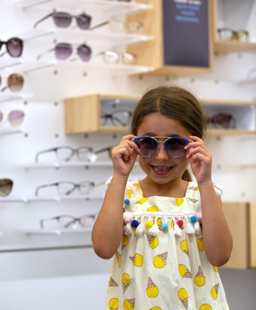 young girl tries on glasses at eyeconic store
