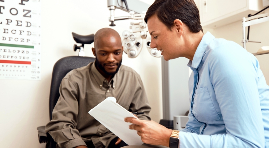 A man and his female eye doctor looking over his eye test results